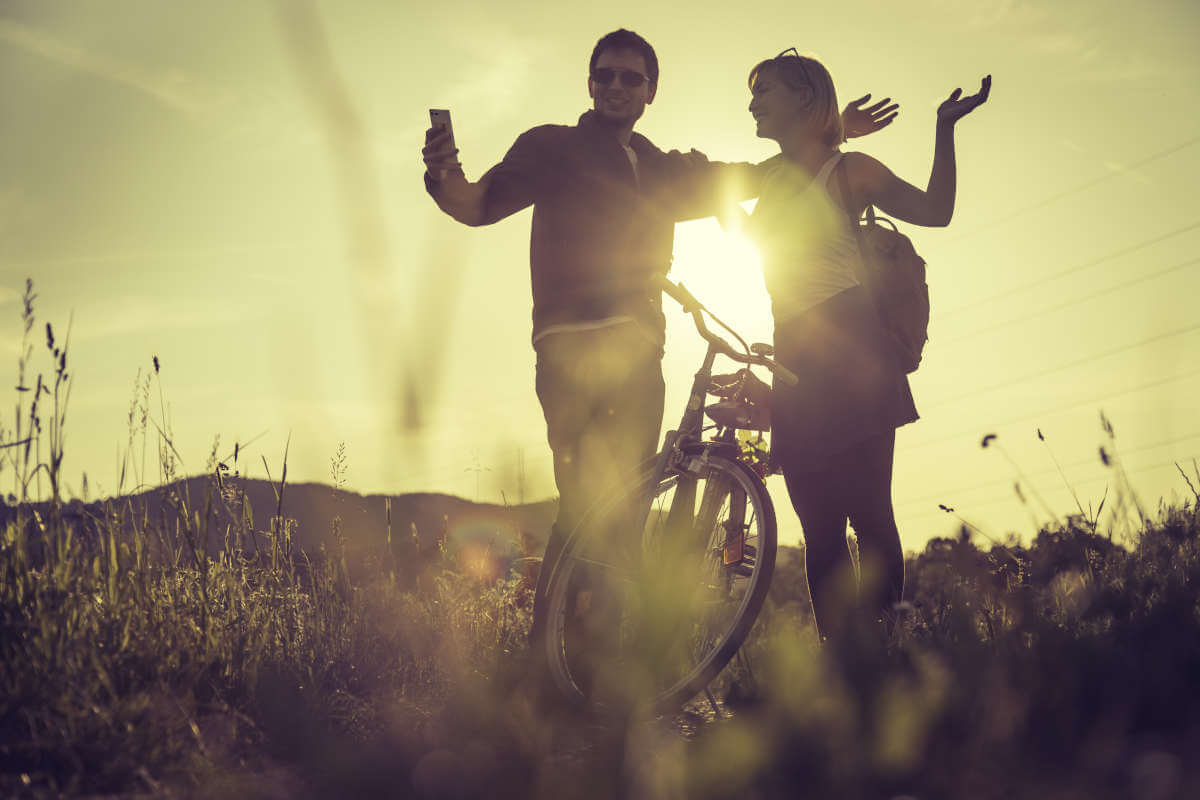 sunset couple standing by a bike